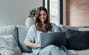 Femme souriante utilisant un ordinateur portable pour une consultation de santé en ligne.