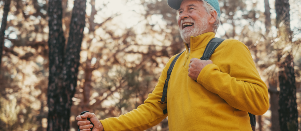 Heureux randonneur senior avec sac à dos et bâtons de randonnée profitant de la nature.