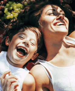 Une mère et son enfant heureux rient ensemble à l'extérieur.